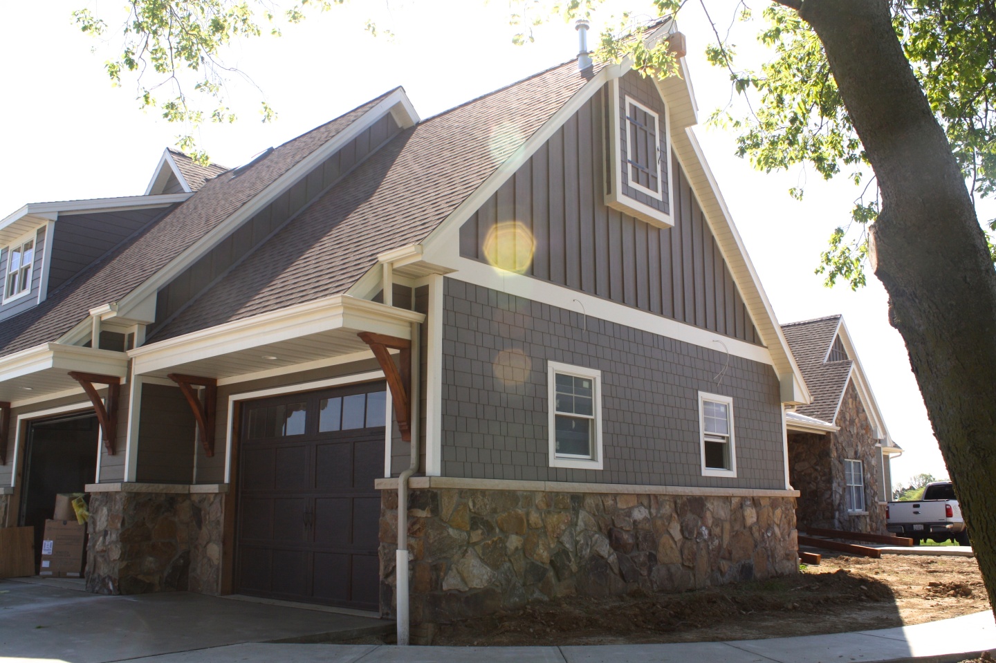 two story farmhouse garage with wooden corbels, stone accents, straight edged shake and vertical siding