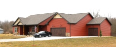 Redwood red siding, wicker tan shakes, dark roof, and wooden garage doors in East Peoria il