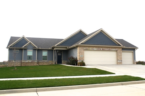 lighter blue siding, dark blue shakes, ranch style home, light tan brick with stone accents light colored garage door