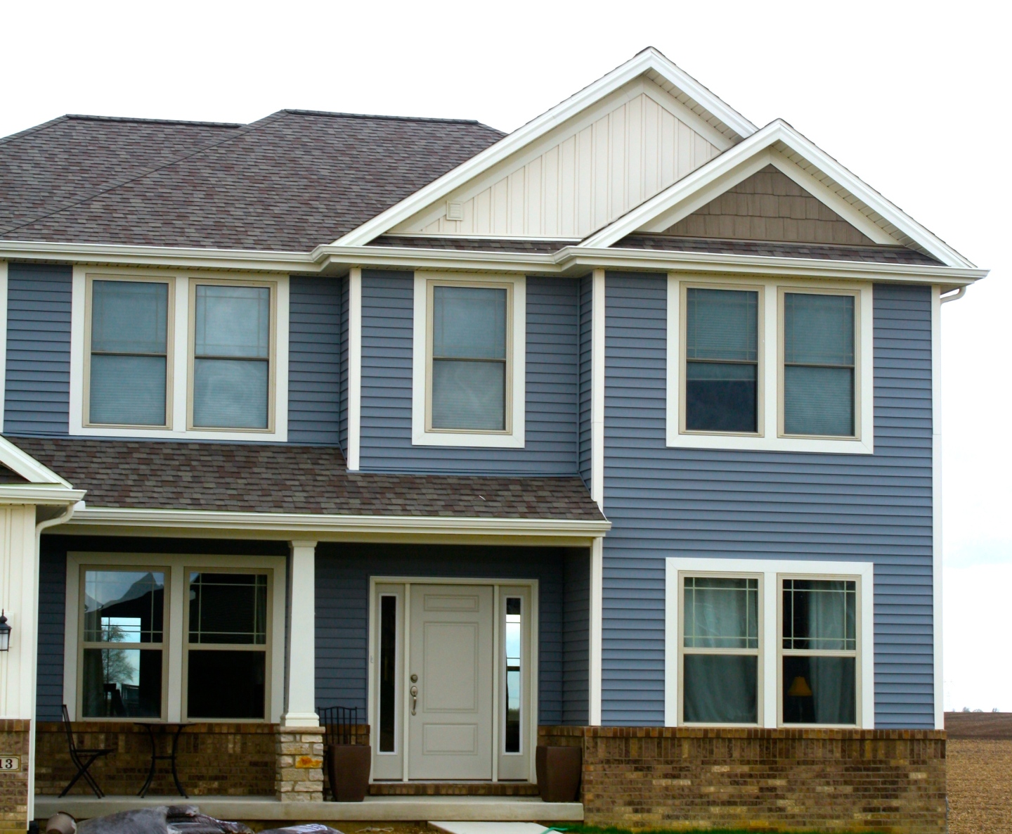 two story blue house with cream and tan accents. Faux cedar skaes